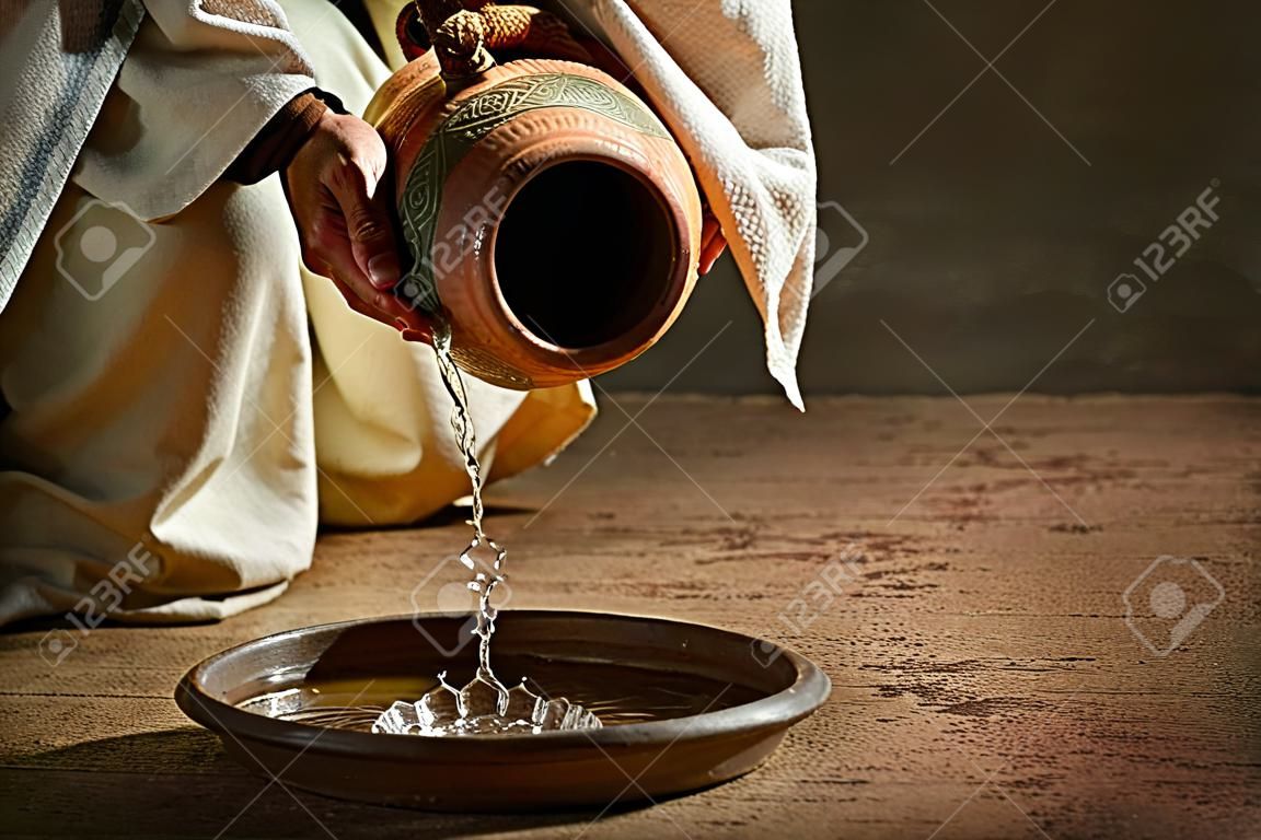 Jezus wylewanie wody z dzbanka na ciemnym tle