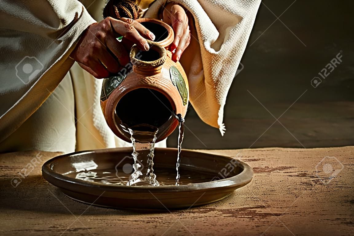Jezus wylewanie wody z dzbanka na ciemnym tle