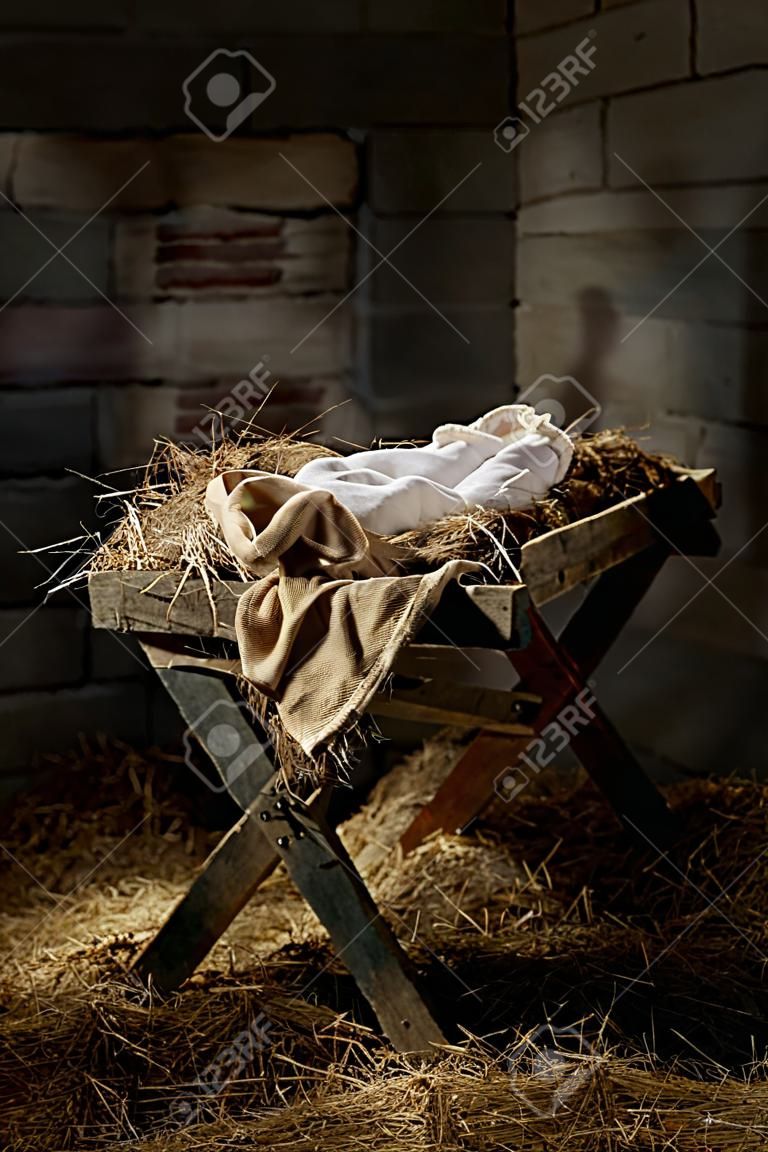 Manger filled with hay in stable with baby soft cloths on top