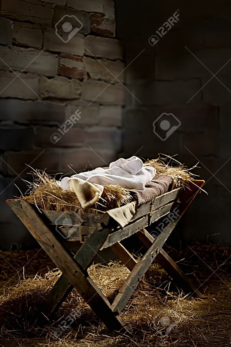 Manger filled with hay in stable with baby soft cloths on top