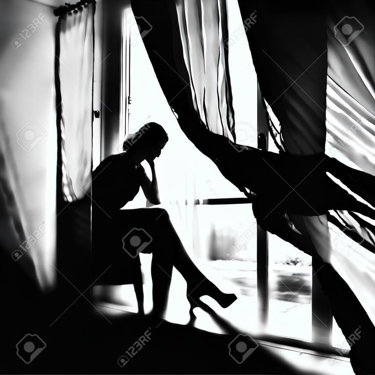 Zwart-wit portret van een bruid aan het raam. Een prachtig silhouet van een vrouw