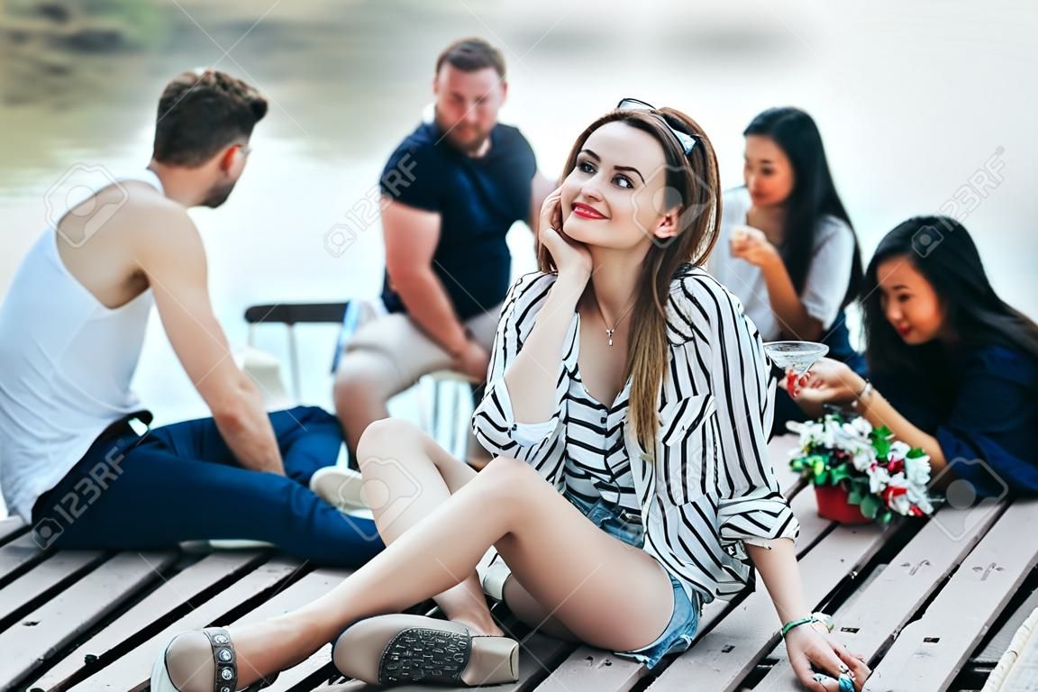 Jovem mulher bonita relaxante por rio em companhia de amigos. Conceito de férias