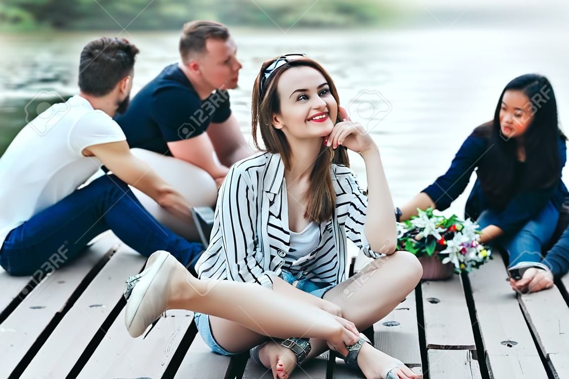 Jovem mulher bonita relaxante por rio em companhia de amigos. Conceito de férias