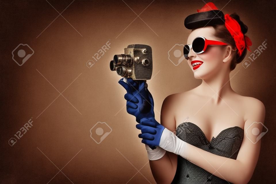 Zdjęcie z pin-up girl w gorset i rękawice gospodarstwa rocznika kamery 8mm.