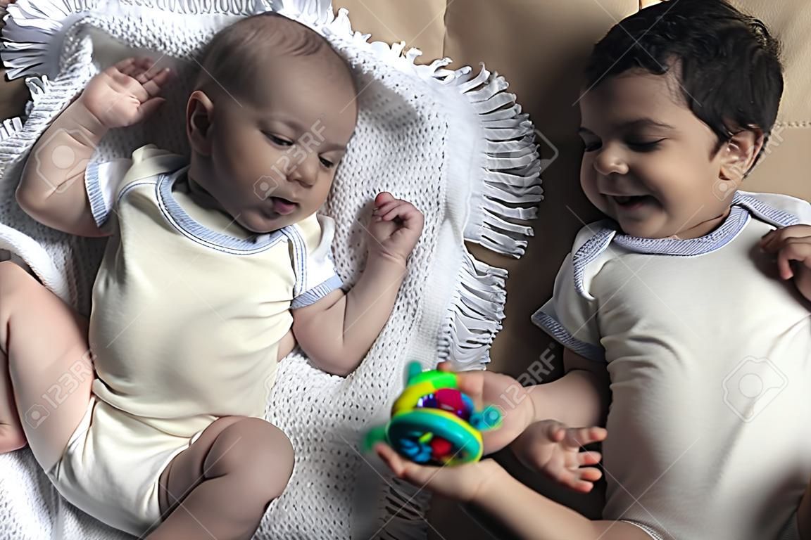 Two brothers lying and posing. Portrait of brothers. Two months baby boy and five years small boy playing cheerfully. View from above. Flat lay photo. Emotional expressions of children.