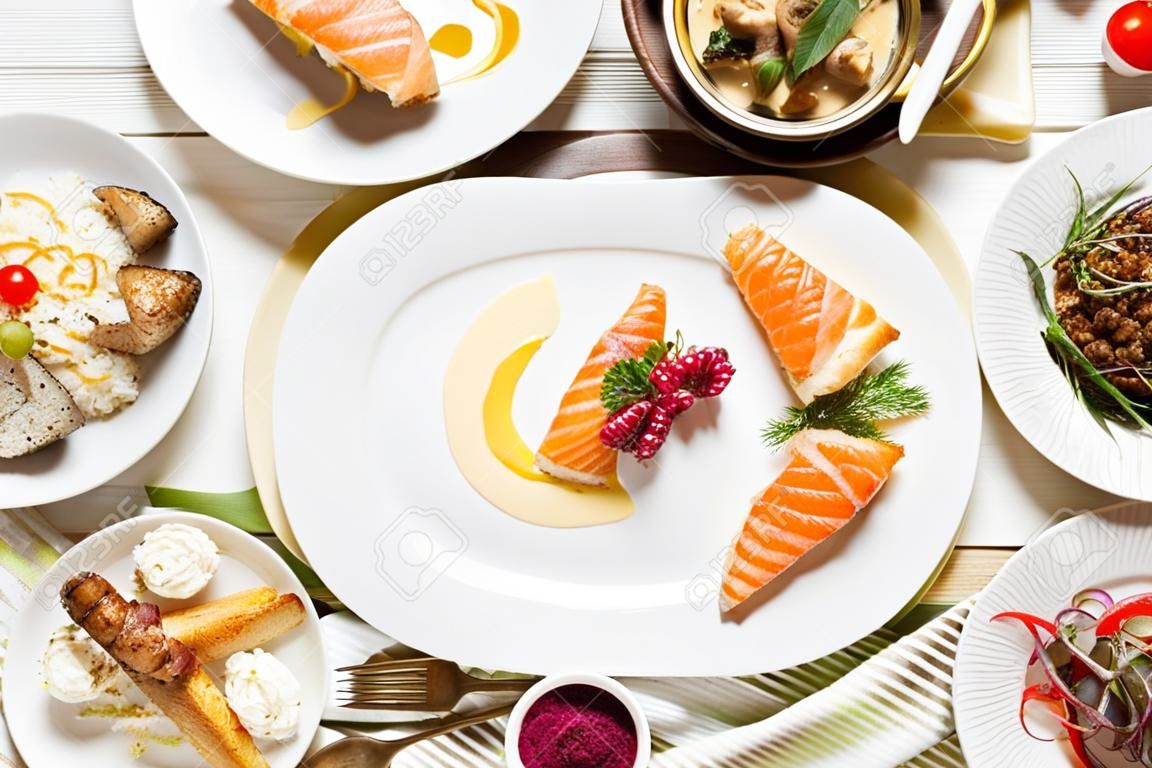 Draufsicht des Lebensmittelsortiments. Luxuriöses Buffet flach. Auswahl an Tellern und Speisen auf weißem Hintergrund