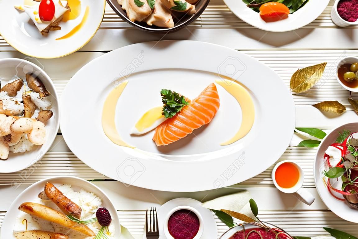 Draufsicht des Lebensmittelsortiments. Luxuriöses Buffet flach. Auswahl an Tellern und Speisen auf weißem Hintergrund