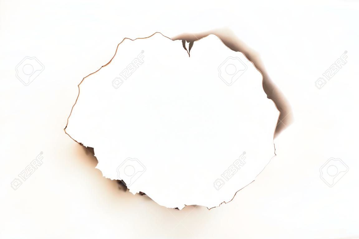 Flat lay of sheet of paper with burnt round hole on white surface. Abstract background. Frame design. Copy space.