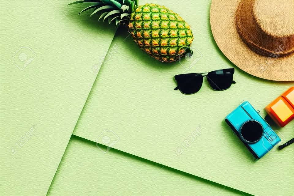Fête d'été. Il est temps de se détendre et de voyager avec des lunettes de soleil, un appareil photo, un chapeau et des fruits d'ananas sur fond pastel. Style de conception vintage