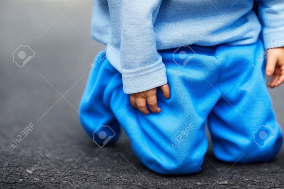 Un joven peeing en sus pantalones en la calle - Bed-wetting concepto. Niño pee en la ropa.