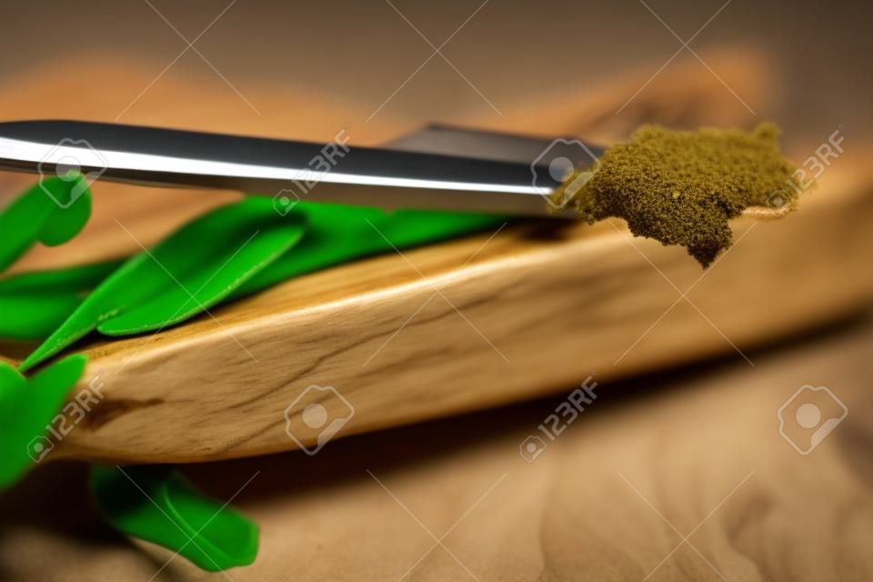 vanilla pod on olive board with beans on knife, close up photo