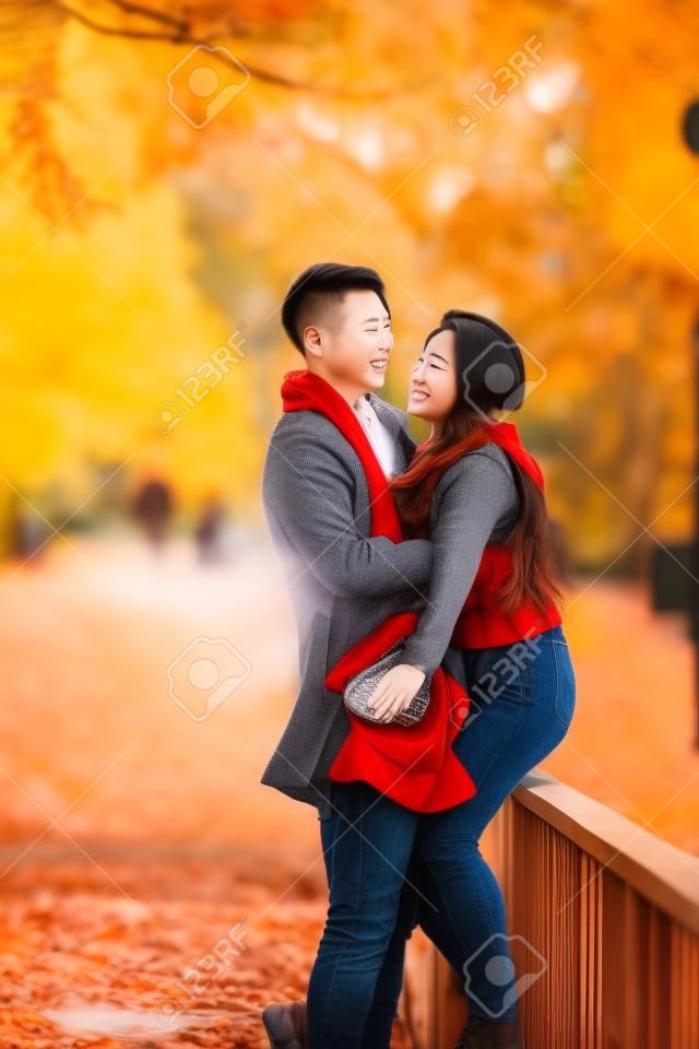 Casal amoroso está abraçando a ponte no parque e desfrutando do belo dia de outono