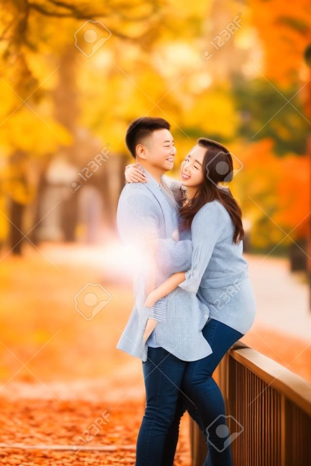 Zakochana para przytula się na moście w parku i cieszy się pięknym jesiennym dniem