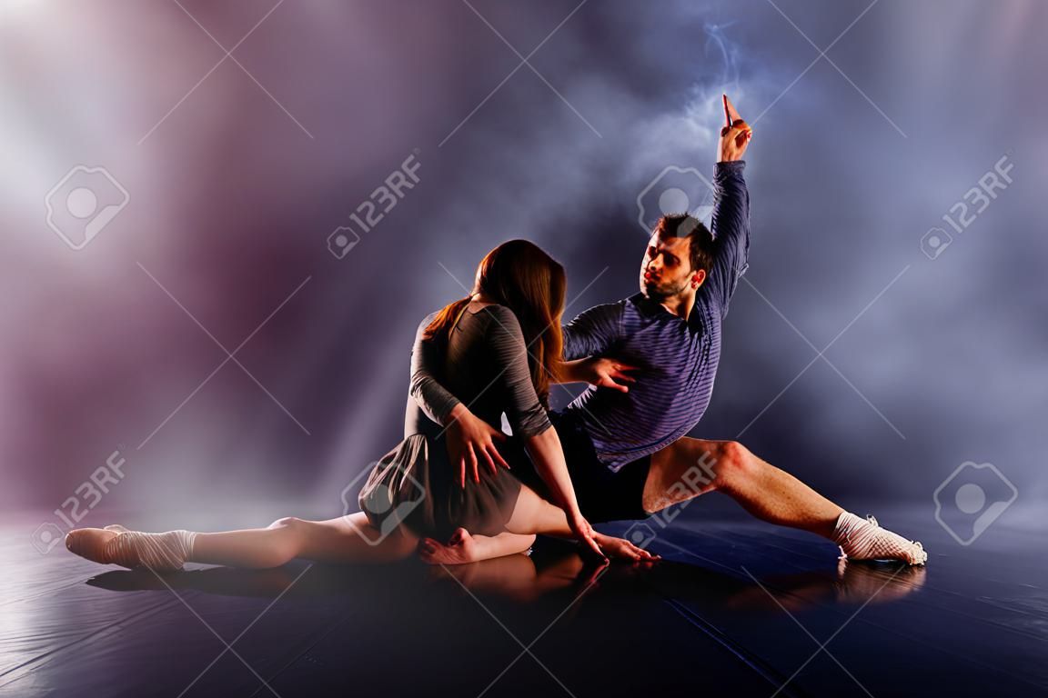 Couple de danse moderne se tordant les jambes et se penchant près du sol, touchant et combinant leurs corps dans une expérience de danse moderne extrêmement unique.