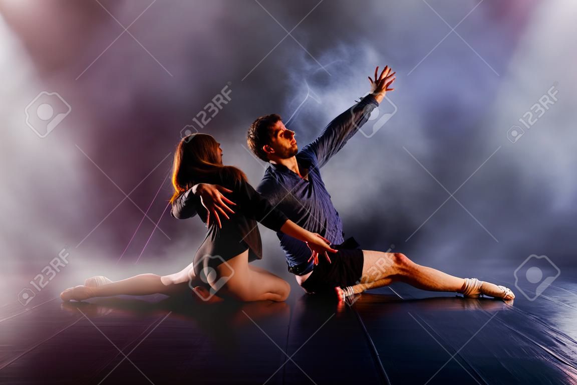 Modernes Tanzpaar, das seine Beine verdreht und sich dicht über den Boden lehnt, berührt und kombiniert seine Körper in einem äußerst einzigartigen modernen Tanzerlebnis.