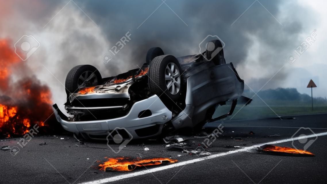 Horrific Traffic Accident, Rollover Smoking and Burning Vehicle Lying on its Roof in the Middle of the Road after Collision. Daytime Crash Scene with Severely Damaged Car.