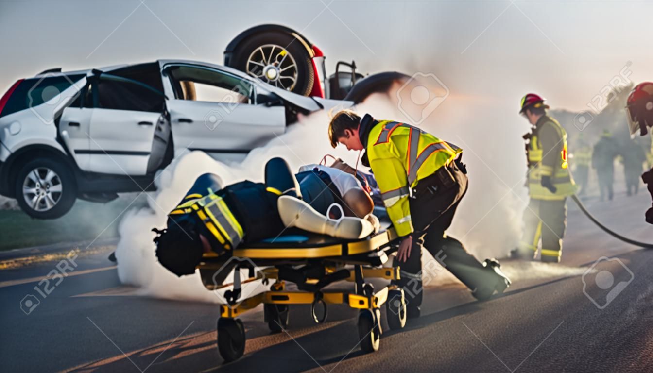 Op de auto-ongeluk verkeer scene: paramedici redden het leven van een vrouw slachtoffer liggen op Stretchers. Ze luisteren naar een hartslag, passen zuurstofmasker en geven eerste hulp. brandweerlieden blussen vuur