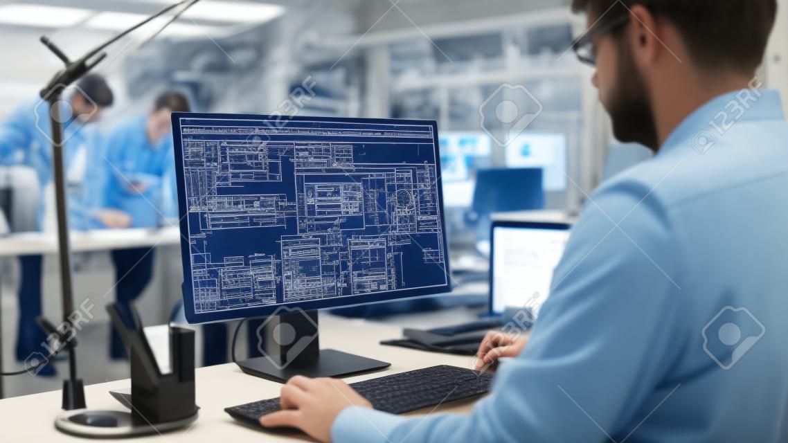 Ujęcie inżyniera pracującego z oprogramowaniem cad na komputerze stacjonarnym przez ramię, ekran pokazuje szkice techniczne i rysunki. w zakładzie inżynierskim specjalizującym się w wzornictwie przemysłowym