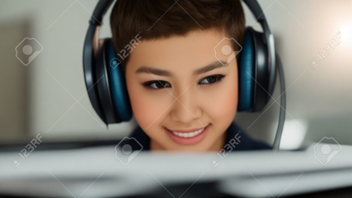 Primer plano retrato de una joven elegante con pelo corto jugando videojuegos de computadora en línea por la noche en casa. jugador discutiendo tácticas con sus compañeros de equipo mientras