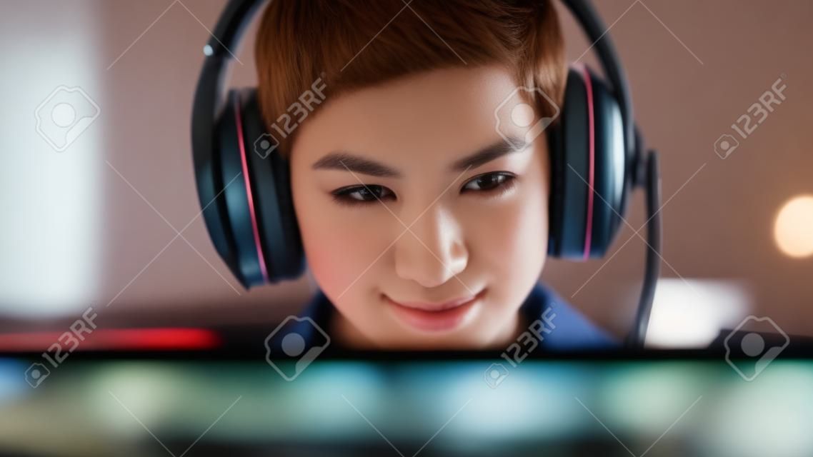저녁에 집에서 온라인 컴퓨터 비디오 게임을 하는 짧은 머리를 가진 세련된 젊은 여성의 초상화를 닫으세요. 게이머가 팀원들과 전술을 논의하는 동안