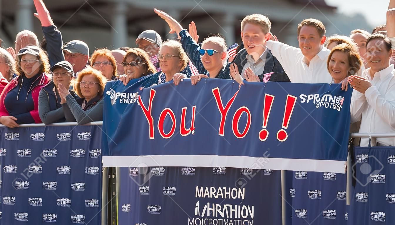 スプリント中に愛する人に手を振るマラソンサポーター モチベーションを高める横断幕を掲げて応援する観客