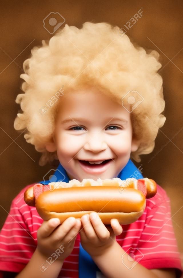 Niño que come el perrito caliente, Kid celebración de perro caliente.