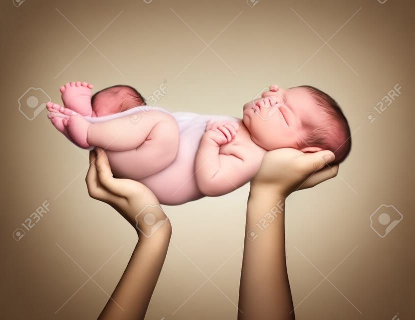 Mãos de mãe segurando um bebê recém-nascido.