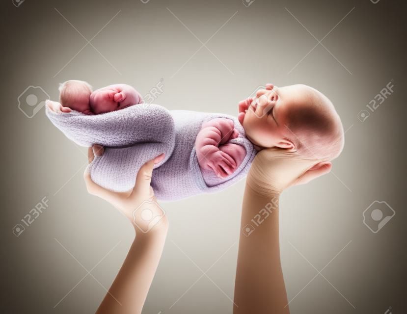 Mother's hands holding a newborn baby.