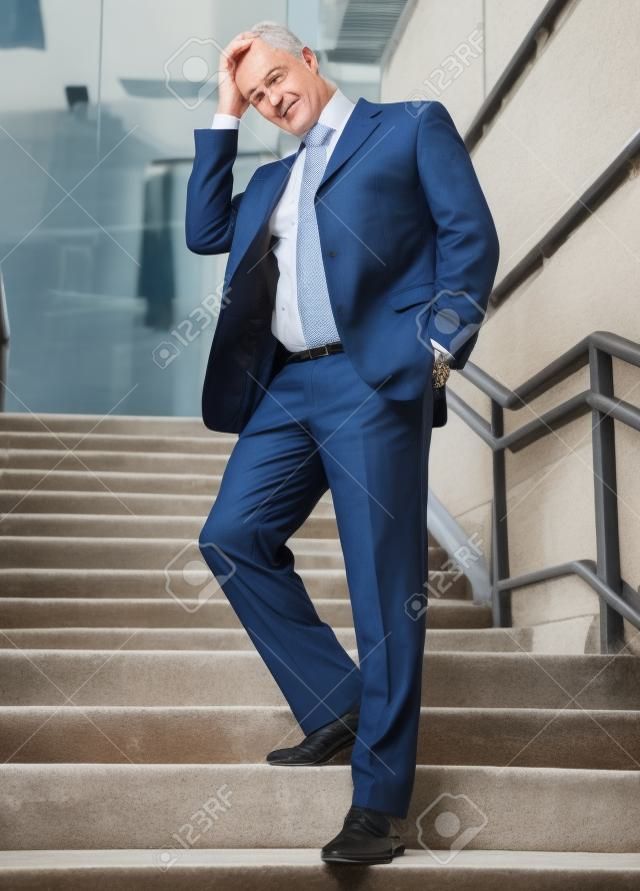 Retrato de um homem de negócios que passa pelas escadas velhas e pensa