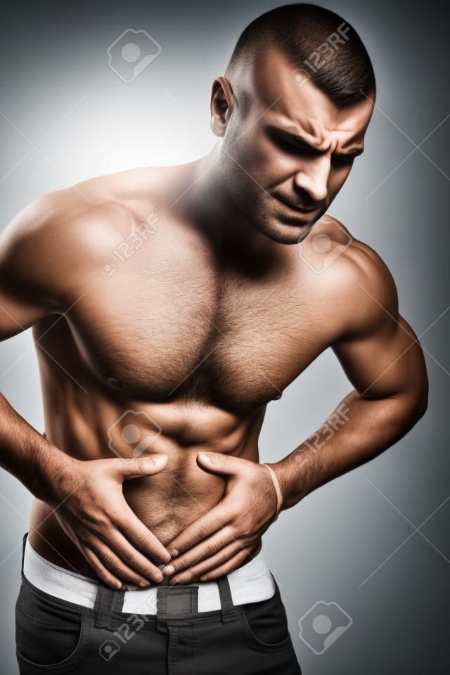 Muskularny mężczyzna trzyma bolesny brzuch
