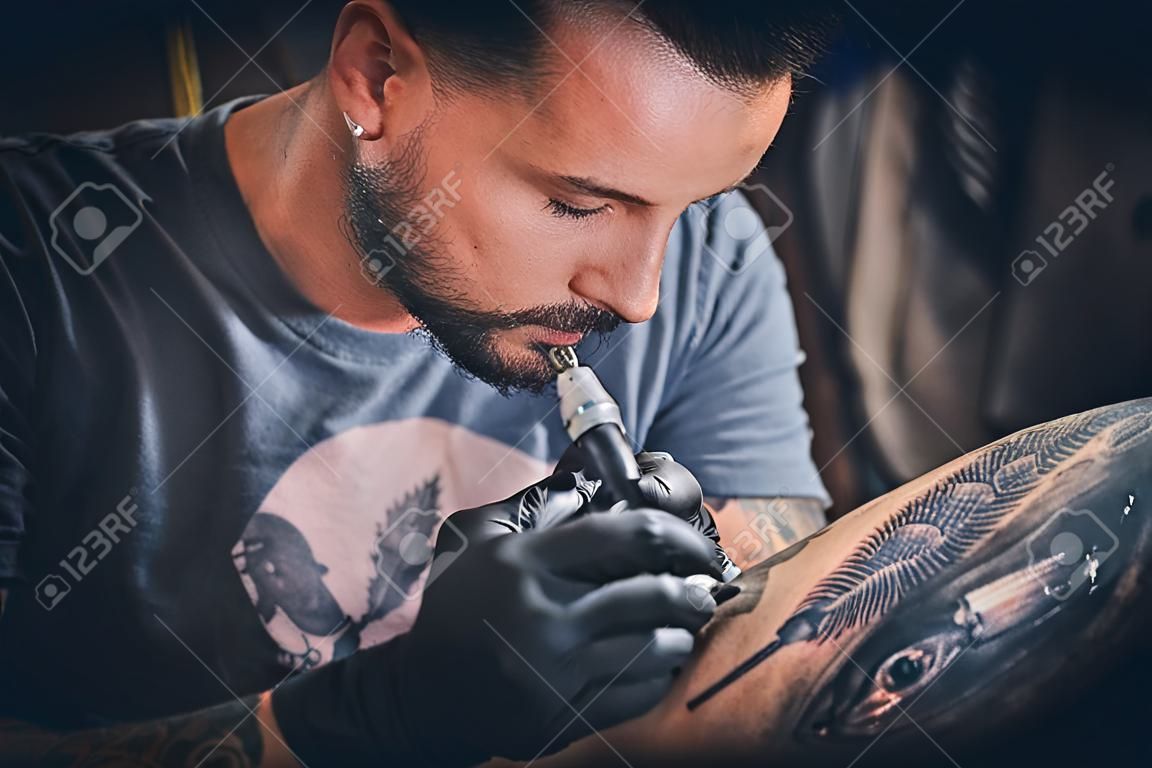 L'artista del tatuaggio professionista fa un tatuaggio sulla mano di un giovane