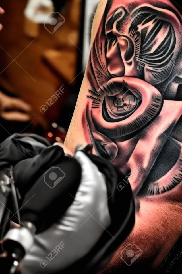 Tattoo artiest het maken van een tatoeage op de arm van een man