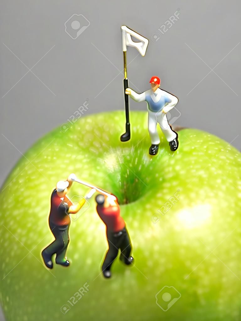 Miniature golf on apple  Macro shot of golfing figurines playing round on top of green apple