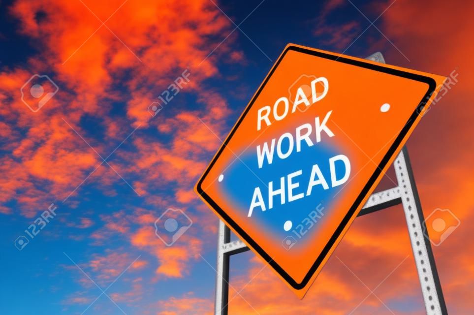 Image of a bright orange road work ahead sign against a blue sky with light clouds