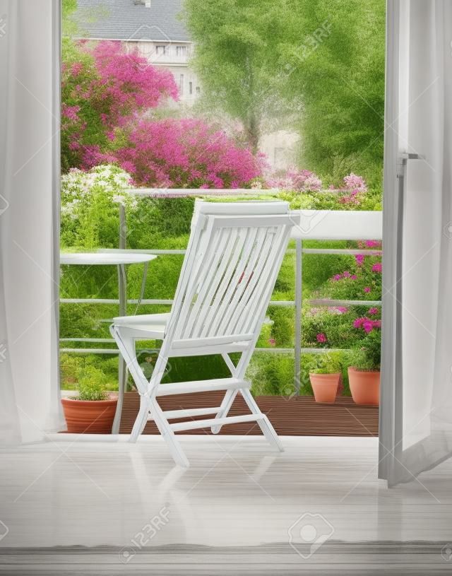 Piękny taras lub balkon z małym stołem, krzesłem i kwiatami. Widok na ogród. Stonowane zdjęcie