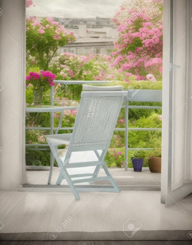Piękny taras lub balkon z małym stołem, krzesłem i kwiatami. Widok na ogród. Stonowane zdjęcie