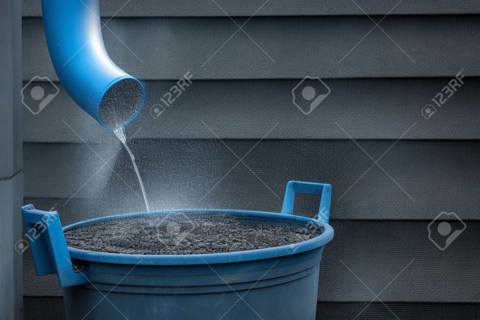 Regenwater schiet vanuit een goot in een waterreservoir