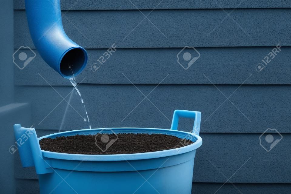 Rainwater shooting from a gutter into a water collecting reservoir