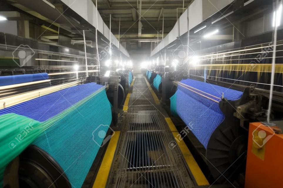 Linha de produção de tecido industrial. Teares de tecelagem em uma fábrica têxtil