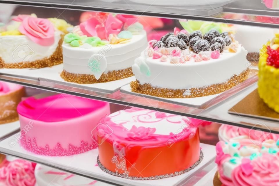 Diferentes tipos de bolos doces na exposição de vidro da loja de pastelaria
