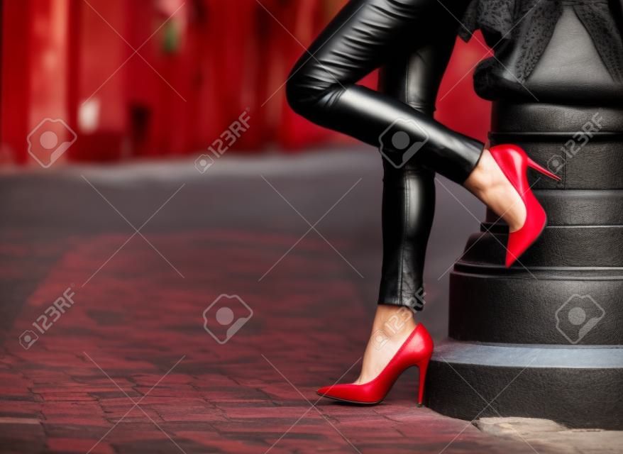 Frau trägt schwarze Lederhosen und roten Schuhen mit hohen Absätzen in der Altstadt