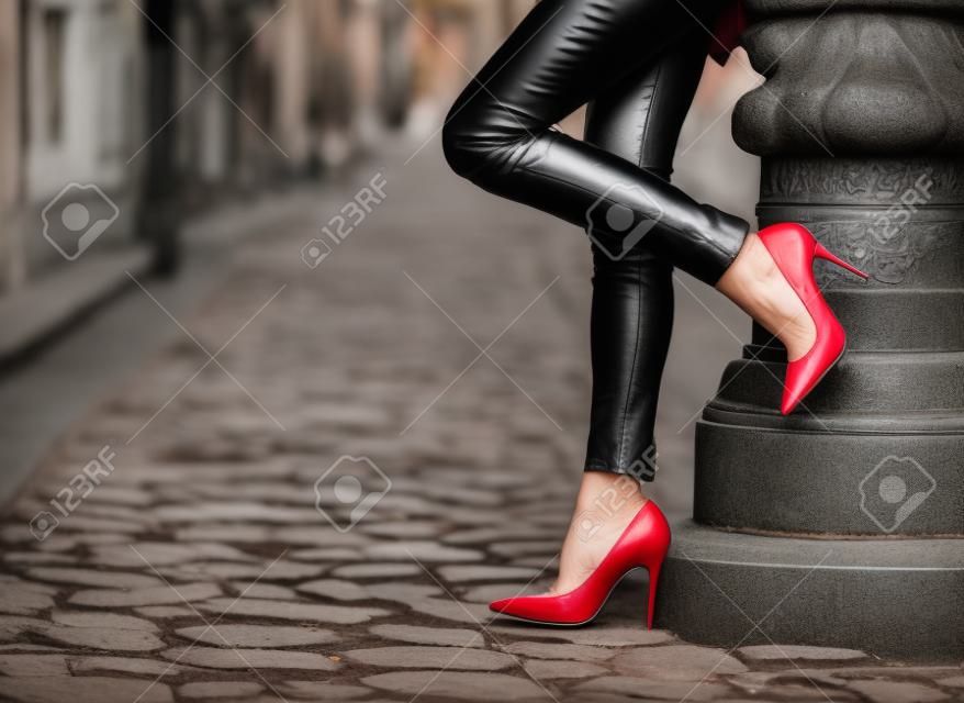 Frau trägt schwarze Lederhosen und roten Schuhen mit hohen Absätzen in der Altstadt