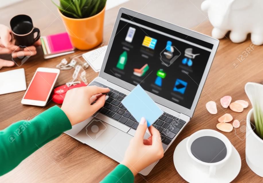 Mujer comprando en línea en una computadora portátil y pagando los bienes comprados con tarjeta de crédito