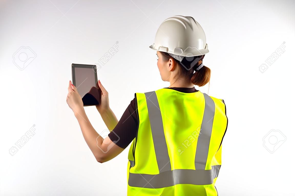 construtor fotografa algo no tablet. Construtor de mulher com tablet eletrônico. Conceito - ela faz relatório de fotos sobre o trabalho feito. Construtor com tablet no fundo branco. Arquiteto no uniforme de trabalho.
