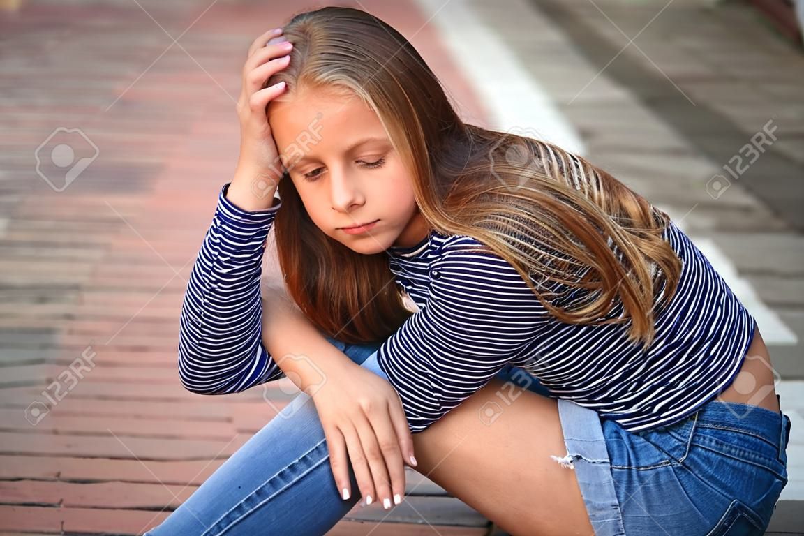 jovem adolescente poses para foto. menina loira em jeans e blusa