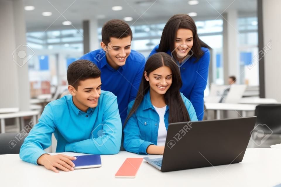 Group of college students studying in the school library, a girl and a boy are using a laptop and connecting to internet