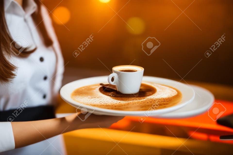 Waitress offering a cup of coffee in cafe. cappuchino