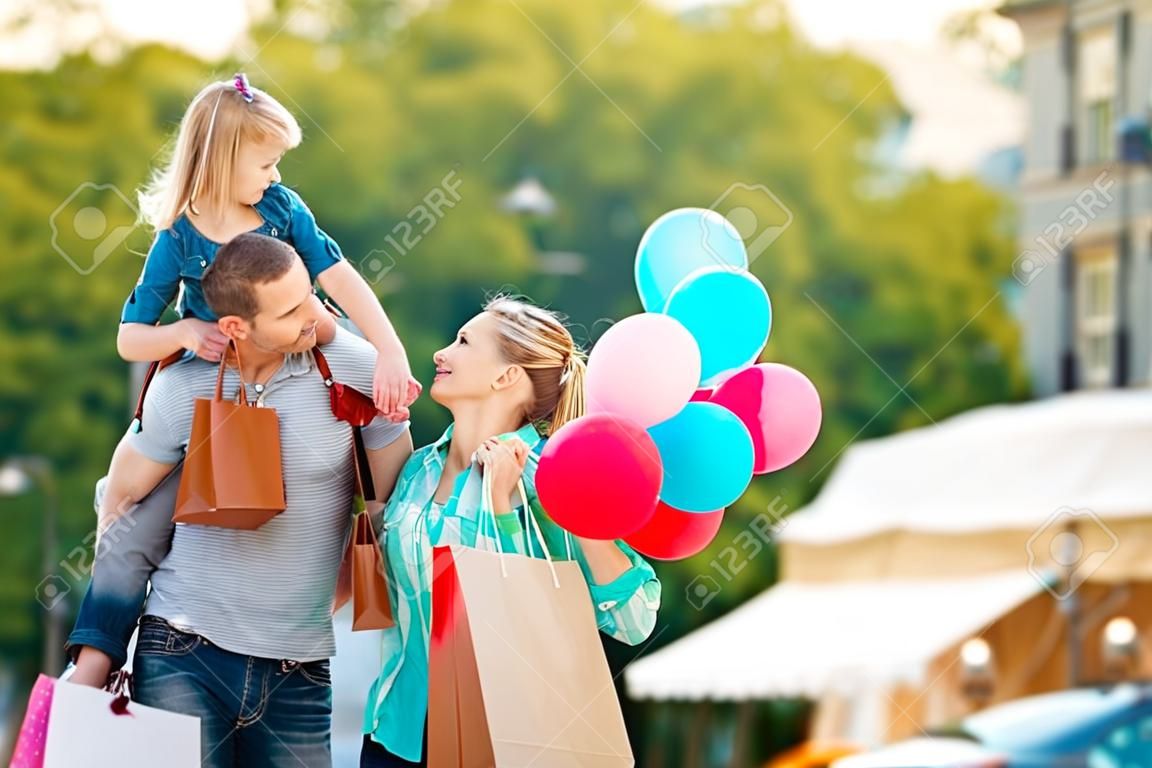 Famiglia felice che cammina lungo la strada con i sacchetti di acquisto.