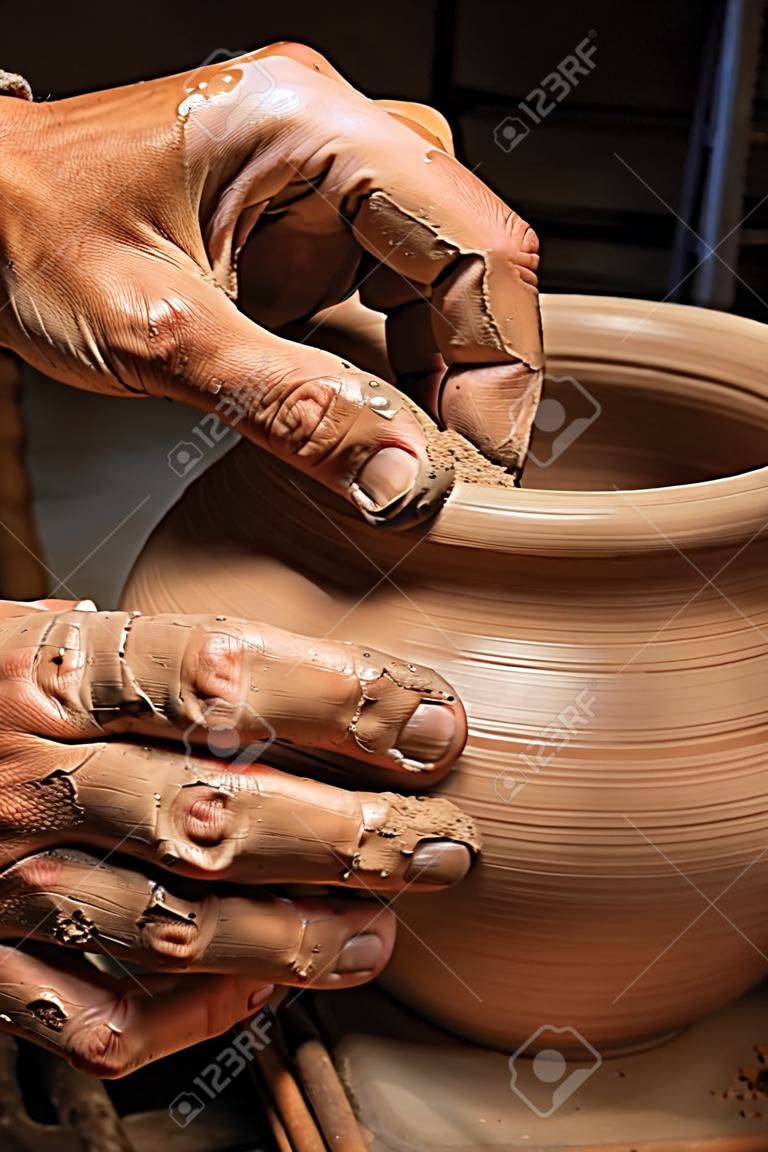 manos de un alfarero, creando una vasija de barro en el círculo