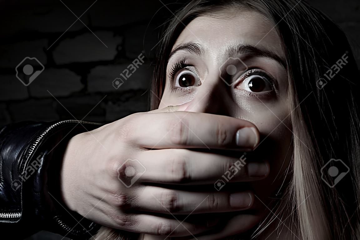Entführung Verängstigt junge Frau mit der Hand über den Mund in die Kamera starrt
